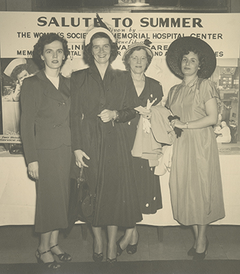Four Society members standing in front of a sign that reads “Salute to Summer.” 