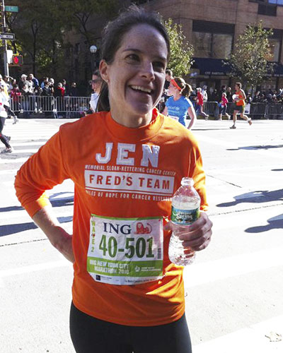 Jennifer Milacci wearing an orange Fred’s Team shirt while running the New York City Marathon to raise money for cancer research at MSK.