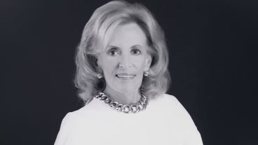 Black and white portrait of a smiling woman with curly hair and a necklace.