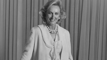Smiling woman in a blazer with a pearl necklace, monochrome photo.