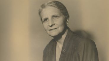 Black-and-white portrait of an older person in a dark suit, smiling slightly.