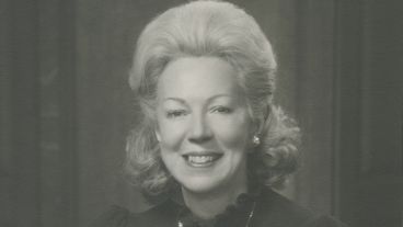 Smiling woman with curled hair in a black and white portrait.