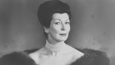 Elegant woman with pearl necklace and earrings, wearing a fur stole. Black and white photo.