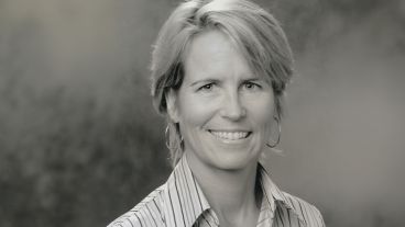 Smiling woman with short hair in a striped shirt, black and white photo.
