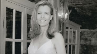 Smiling woman in formal attire standing by glass doors. Black and white photo.