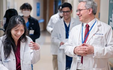 A group of MSK clinicians, including leukemia cancer specialist Dr. Ivan Maillard smiling in a hallway at MSK.  