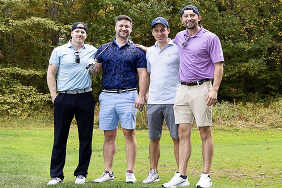 Four people standing on a golf course at a charity golf event benefiting MSK.