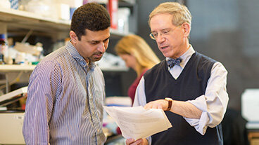 Dr. Kenneth Offit and an MSK researcher in a lab reviewing a document. 